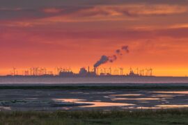 The Wadden Sea, factory buildings and wind turbines at sunset, Eemshaven, Netherlands.