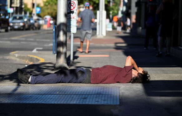 A man lies on a sidewalk during a heatwave in Portland, Oregon, U.S, on 11 August 2021.