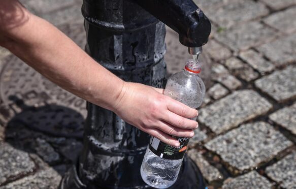 A person pours tap water into a plastic bottle at the Main Square in Krakow, Poland, on 19 June 2022.