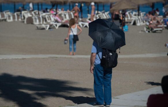 A man is seen at a near-empty 'La Malagueta beach' during an unusual heat wave on 26 April 2023.