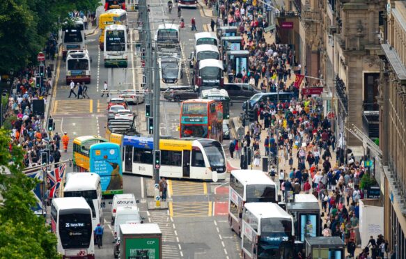 Heavy public transport traffic and pedestrians on Princes Street in Edinburgh, Scotland, UK.