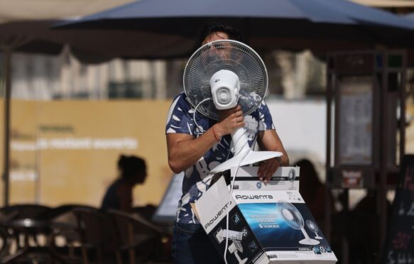 A man carries a fan in Montpellier as the highest temperature reaches 38 degrees centigrade.