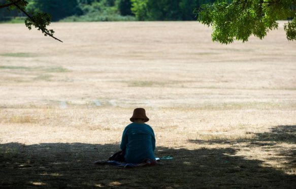 A woman sits in the shade at Primrose Hill during the severe heatwave, London, UK, 19 July 2022. Credit: xStephen Chung / Alamy Stock Photo.