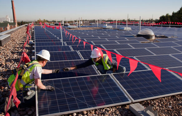 Workers install solar panels on the roof of an elementary school in Colorado.