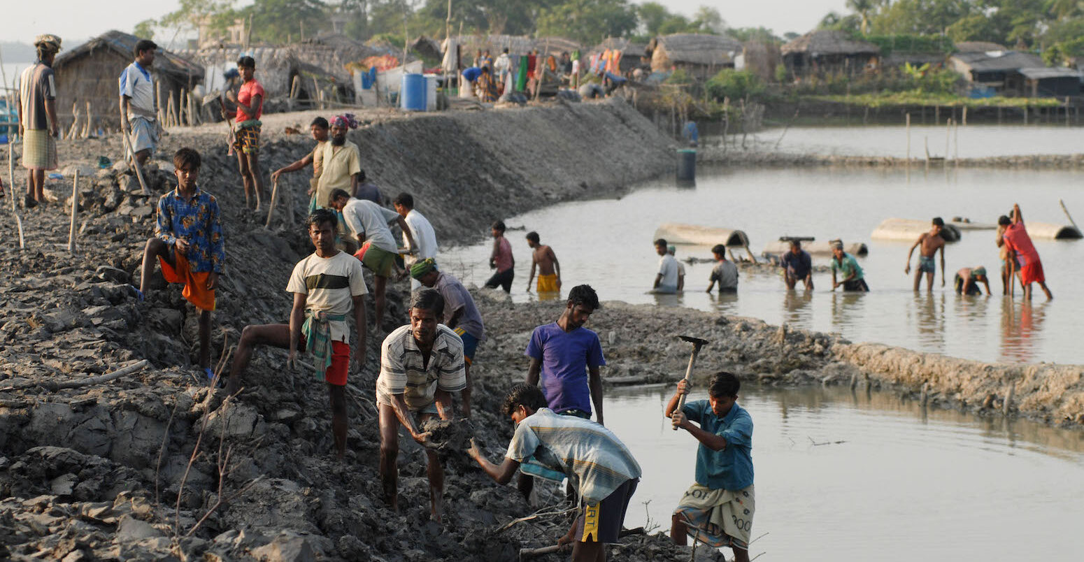 People repairing flood defence in a village in Bangladesh near the bay of Bengal.