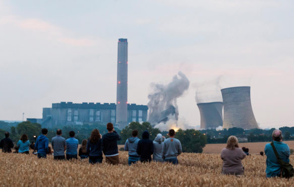 A field of people watch from a distance as the iconic cooling towers of Didcot A coal power station are demolished