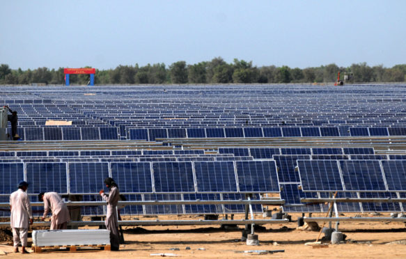 Workers install solar photovoltaic panels in Pakistan.