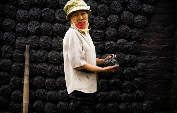 Female worker forms coal patties near Hanoi, Vietnam