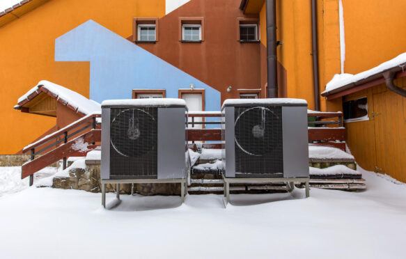 Two residential heat pumps buried in snow. Credit: Radu Sebastian / Alamy Stock Photo