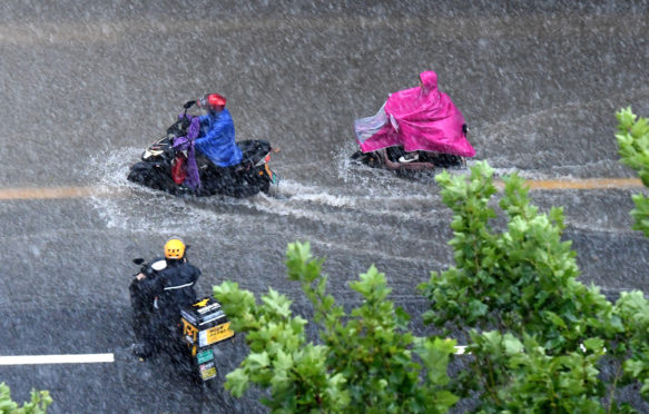 People ride on a waterlogged road in Zhengzhou after torrential rains