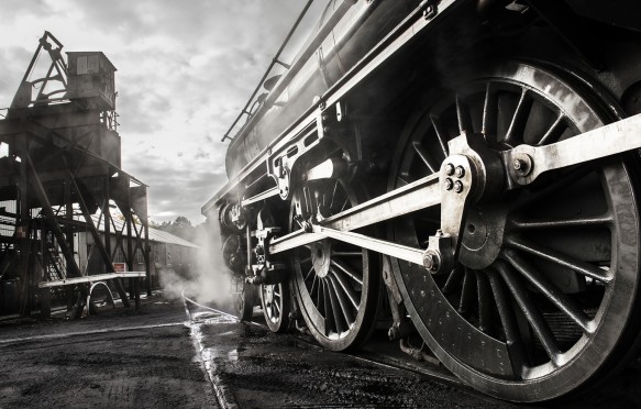 A steam train waiting to receive water from a water tower at a station in North Yorkshire.