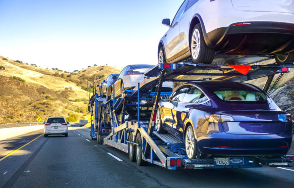 A car transporter carries new Tesla Model 3 vehicles along the highway, California, US. Credit: Andrei Stanescu / Alamy Stock Photo. R6HR26
