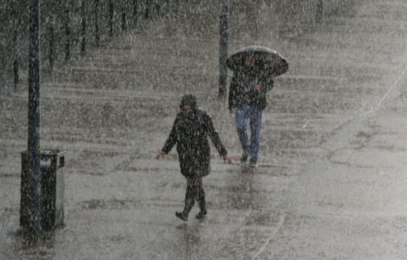 Two people hurry along the Southbank in London as torrential downpour continues